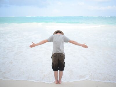 Traveller with arms wide by the water at Diani beach.