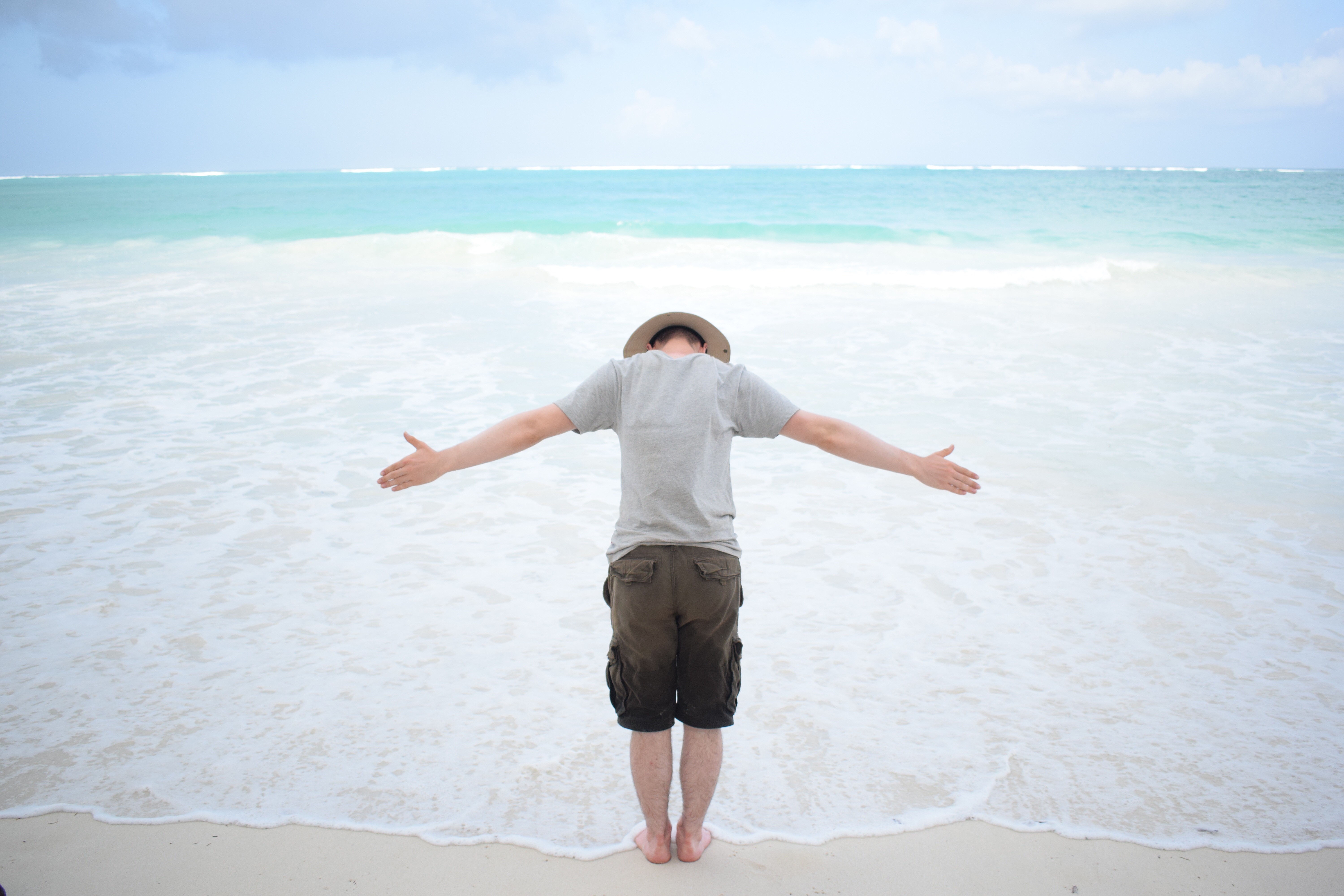 Traveller with arms wide by the water at Diani beach.