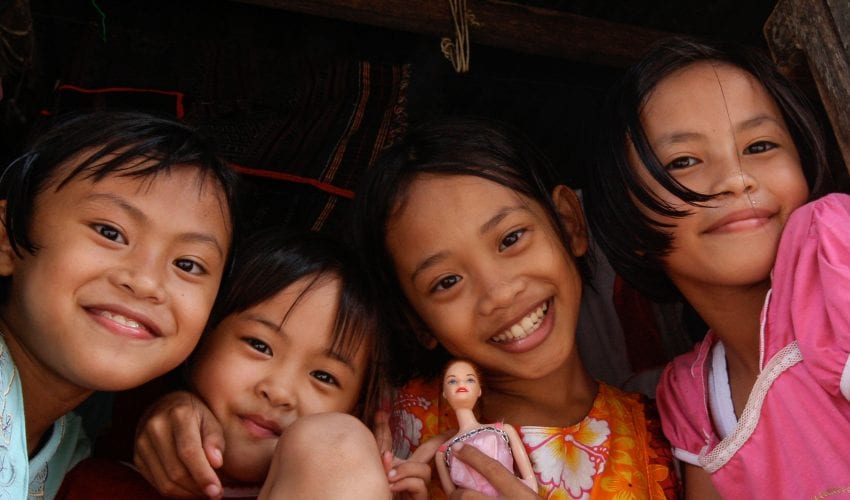 4 young local children smiling and posing together for a photo in Borneo