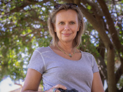 Portrait photo of Anna Lusty, NGO and documentary portrait photographer. She has short blonde hair and is wearing a grey short sleeve tshirt, looking at the camera and smiling