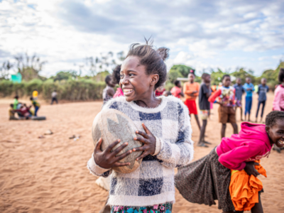 Photograph taken in Africa by photographer Anna Lusty. A group of African school children playing ball at break time at school.
