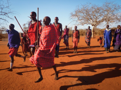 A group of Maasai jumping up and down during a cultural exchange, wearing traditional garments