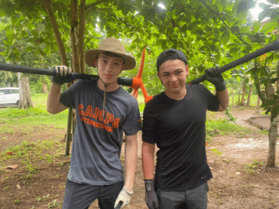 Two travellers wearing hats and gloves and carrying tools in Costa Rica