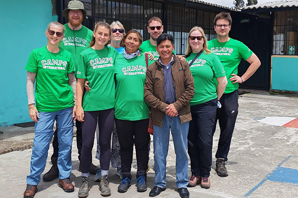 Team in Camp Ecuador t-shirts in front of the community school on an Ecuador teacher inspection visit